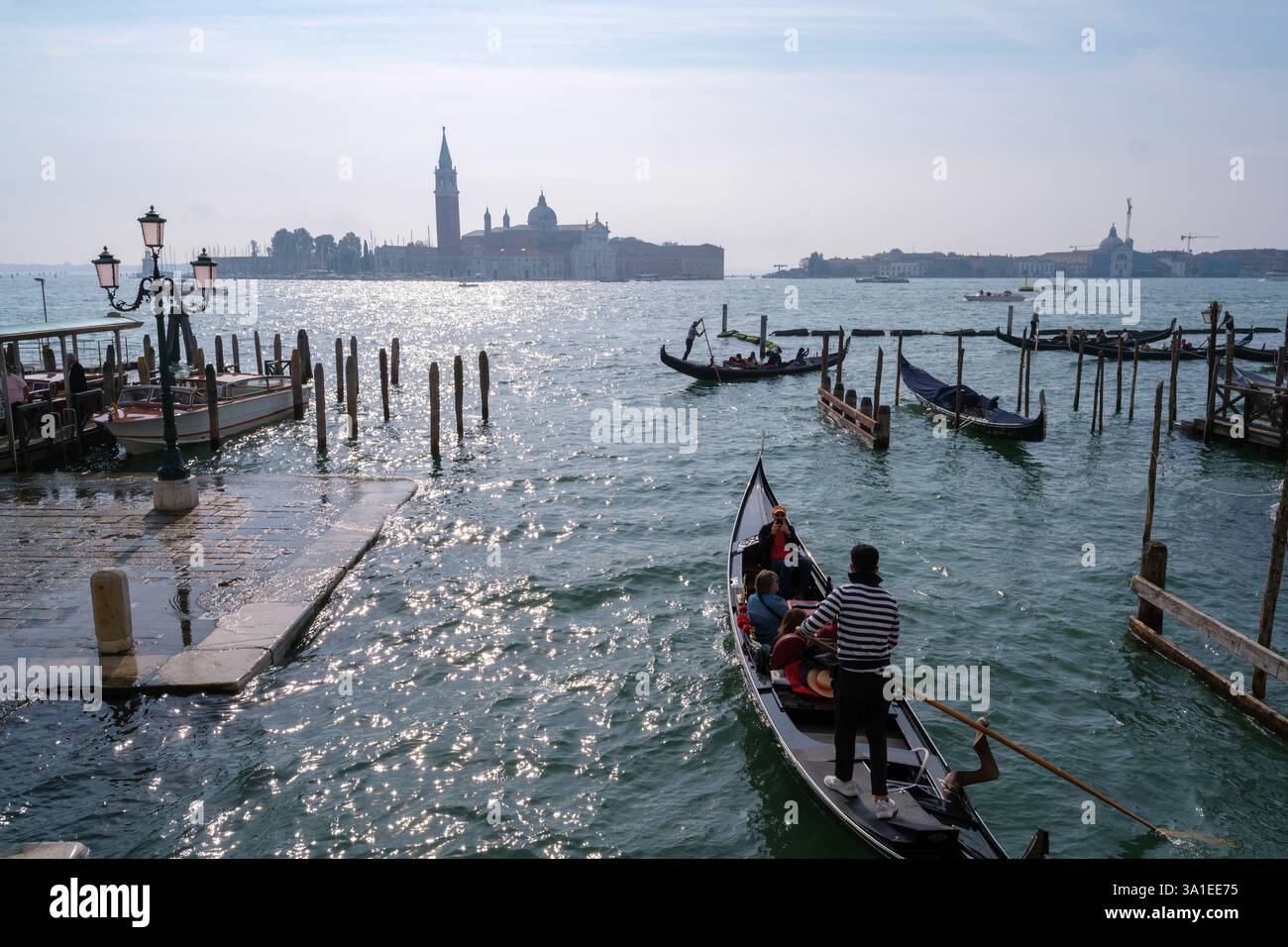 Venezia, Italia - 12 ottobre 2024: Gondole tradizionali che navigano nelle scintillanti acque della laguna veneta vicino a San Giorgio maggiore Foto Stock