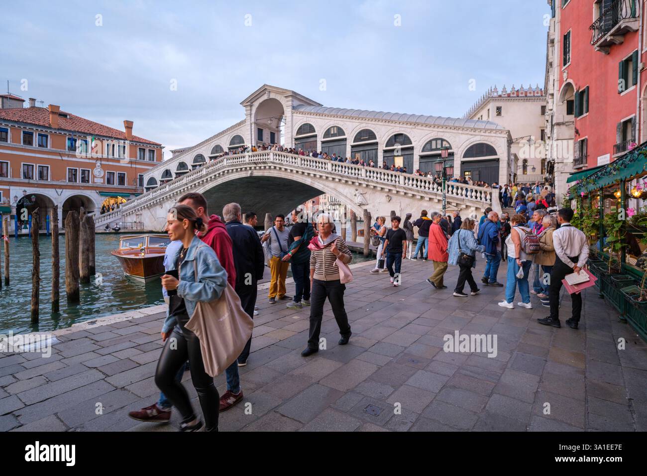 Venezia, Italia - 12 ottobre 2024: Turisti che camminano vicino al Ponte di Rialto sul Canal grande, un famoso punto di riferimento storico affollato di visitatori Foto Stock