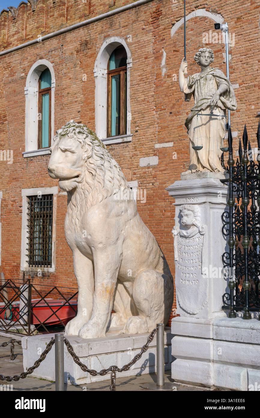 Venezia, Italia - 12 ottobre 2024: Vista ravvicinata di una statua di leone in marmo e di una figura della giustizia all'ingresso dell'Arsenale di Venezia Foto Stock