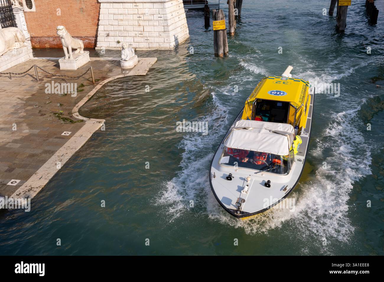 Venezia, Italia - 12 ottobre 2024: Un'imbarcazione di servizio medico di emergenza Venezia accelera nell'acqua vicino alla zona di San Marco con statue di leoni Foto Stock