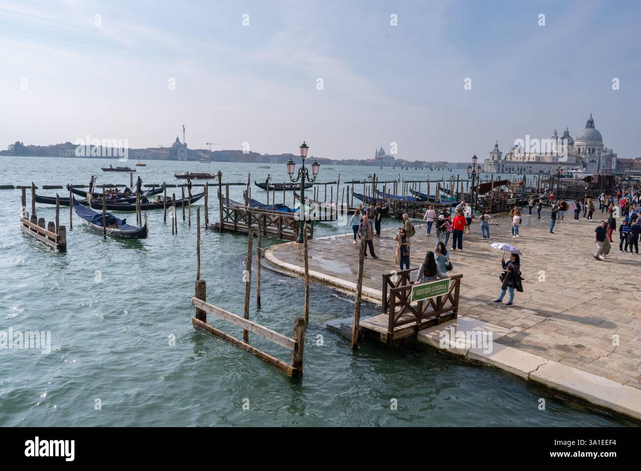 Venezia, Italia - 12 ottobre 2024: Gondole tradizionali che navigano nelle scintillanti acque della laguna veneta vicino a San Giorgio maggiore Foto Stock