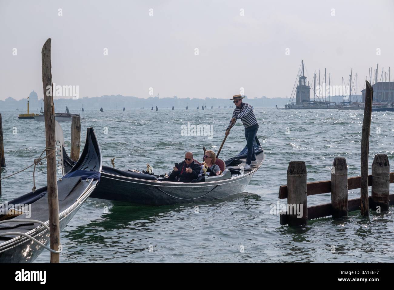 Venezia, Italia - 12 ottobre 2024: Gondole tradizionali che navigano nelle scintillanti acque della laguna veneta vicino a San Giorgio maggiore Foto Stock