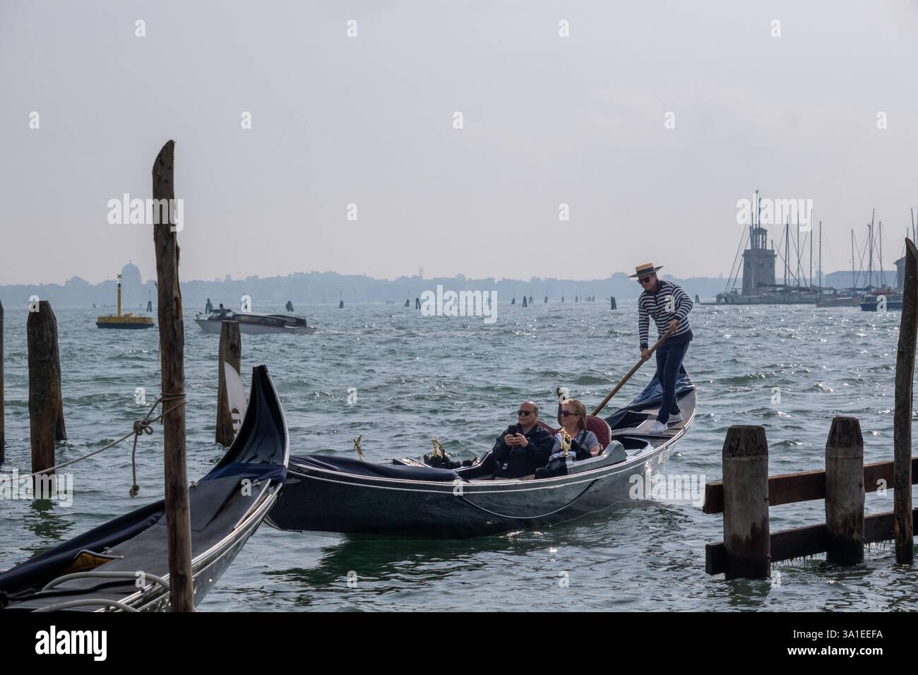 Venezia, Italia - 12 ottobre 2024: Gondole tradizionali che navigano nelle scintillanti acque della laguna veneta vicino a San Giorgio maggiore Foto Stock