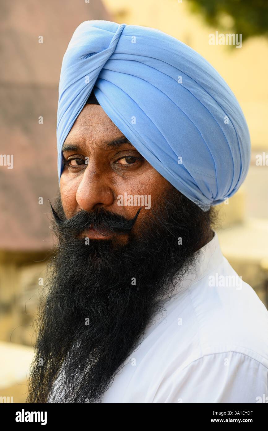 Jaipur, Rajasthan, India - 17 febbraio 2025: Ritratto di un uomo Sikh che indossa un turbante Blue Dastar con la lunga barba nera. Foto Stock