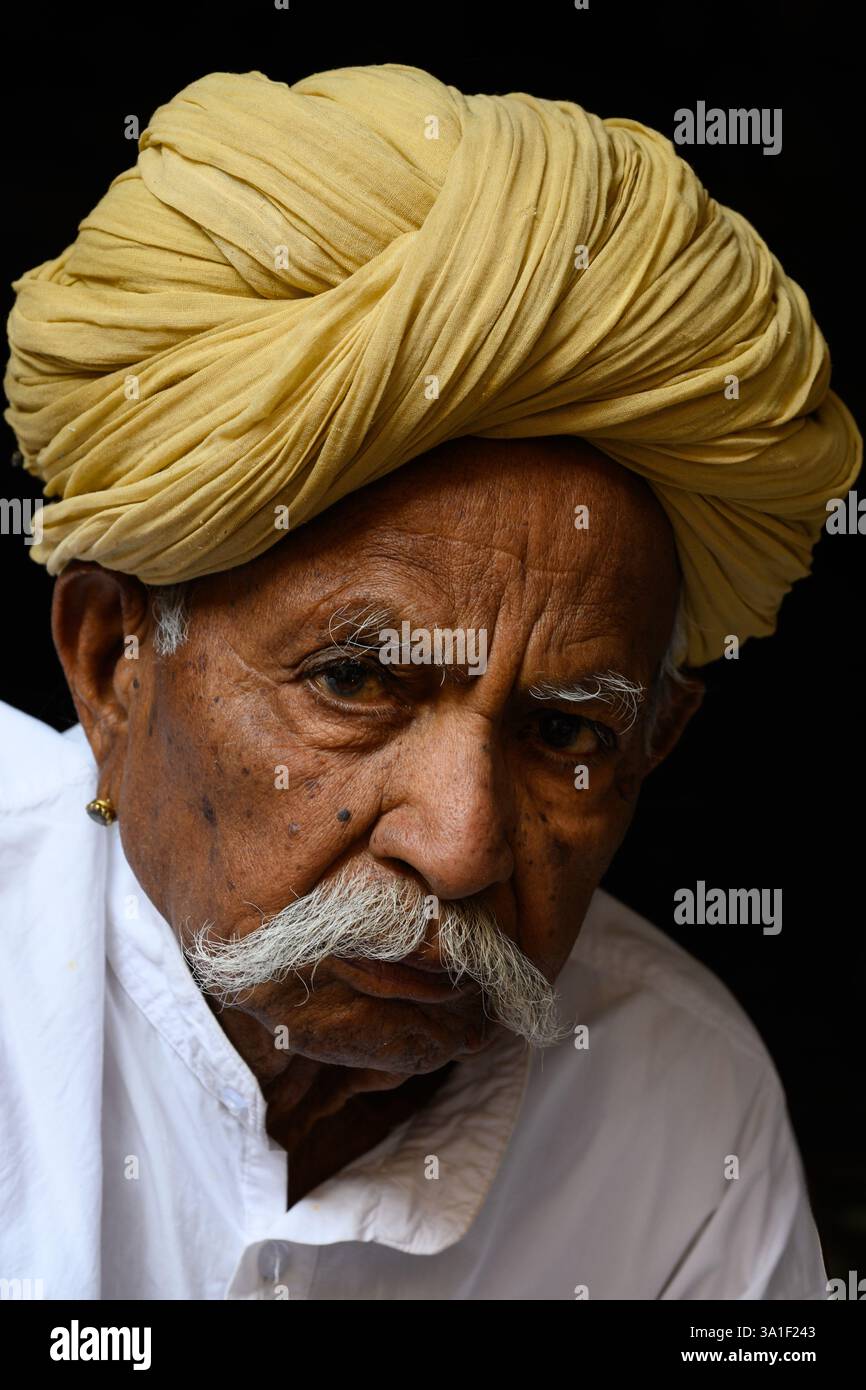 Jaisalmer, Rajasthan, India - 12 febbraio 2025: Uomo Rajasthani che indossa un turbante giallo Safa con baffi grigi e abito tradizionale bianco Foto Stock