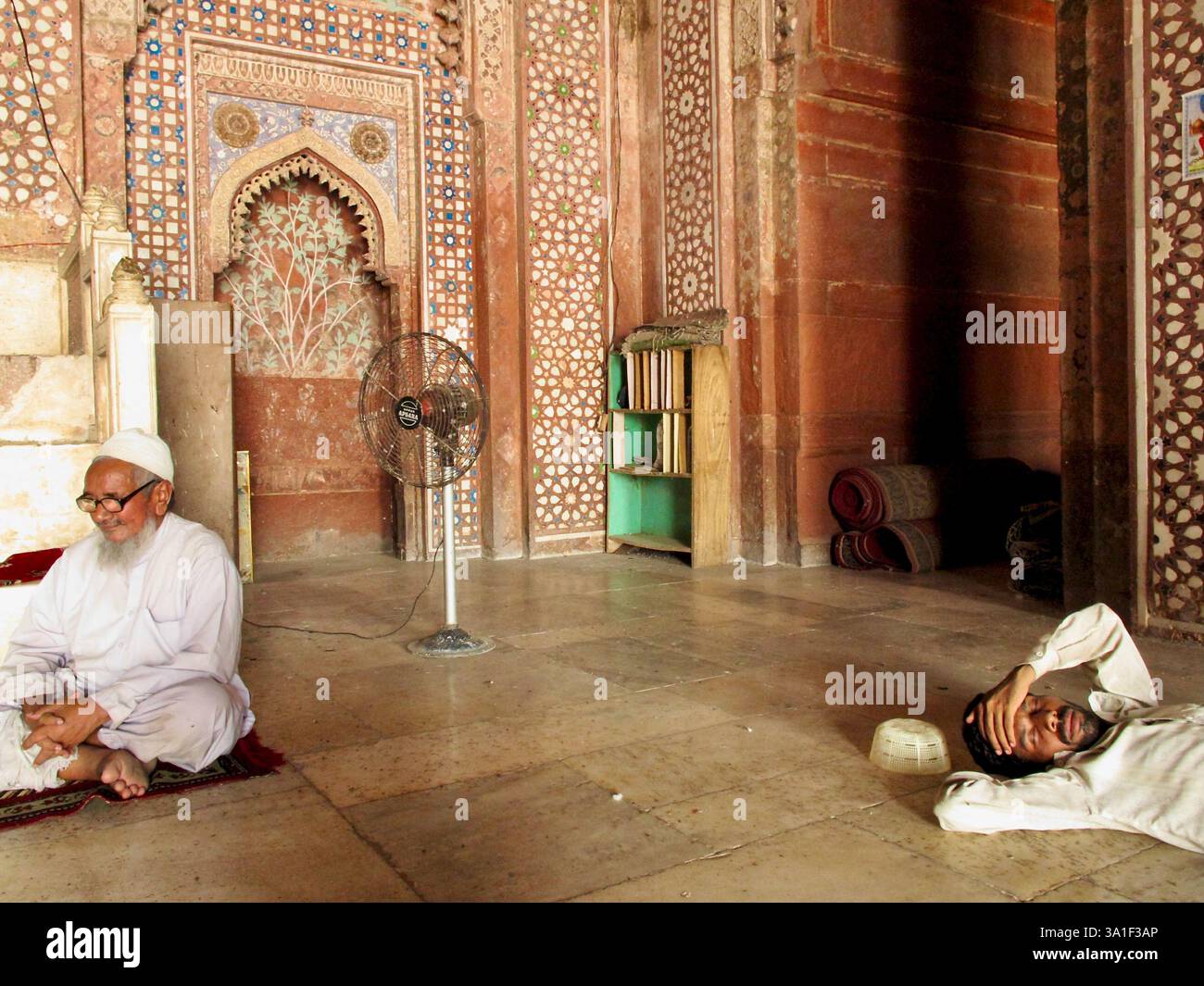 Gli uomini riposano e riflettono all'interno della sala di preghiera ornata di Jama Masjid a Fatehpur Sikri, Uttar Pradesh, India. Foto Stock
