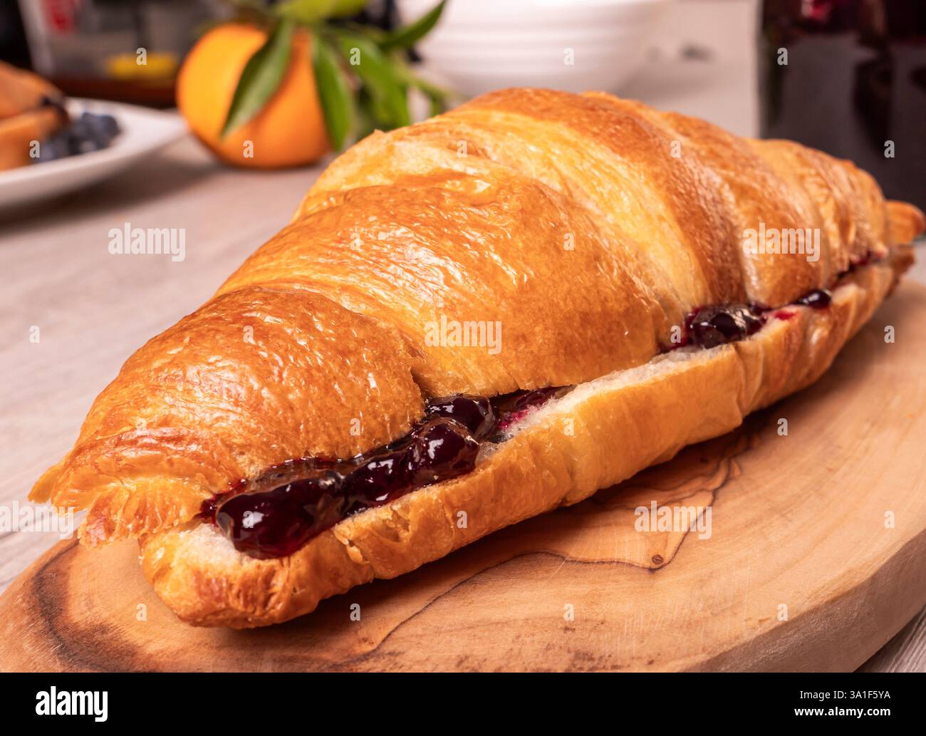 Primo piano di un croissant pieno di marmellata su un tagliere Foto Stock