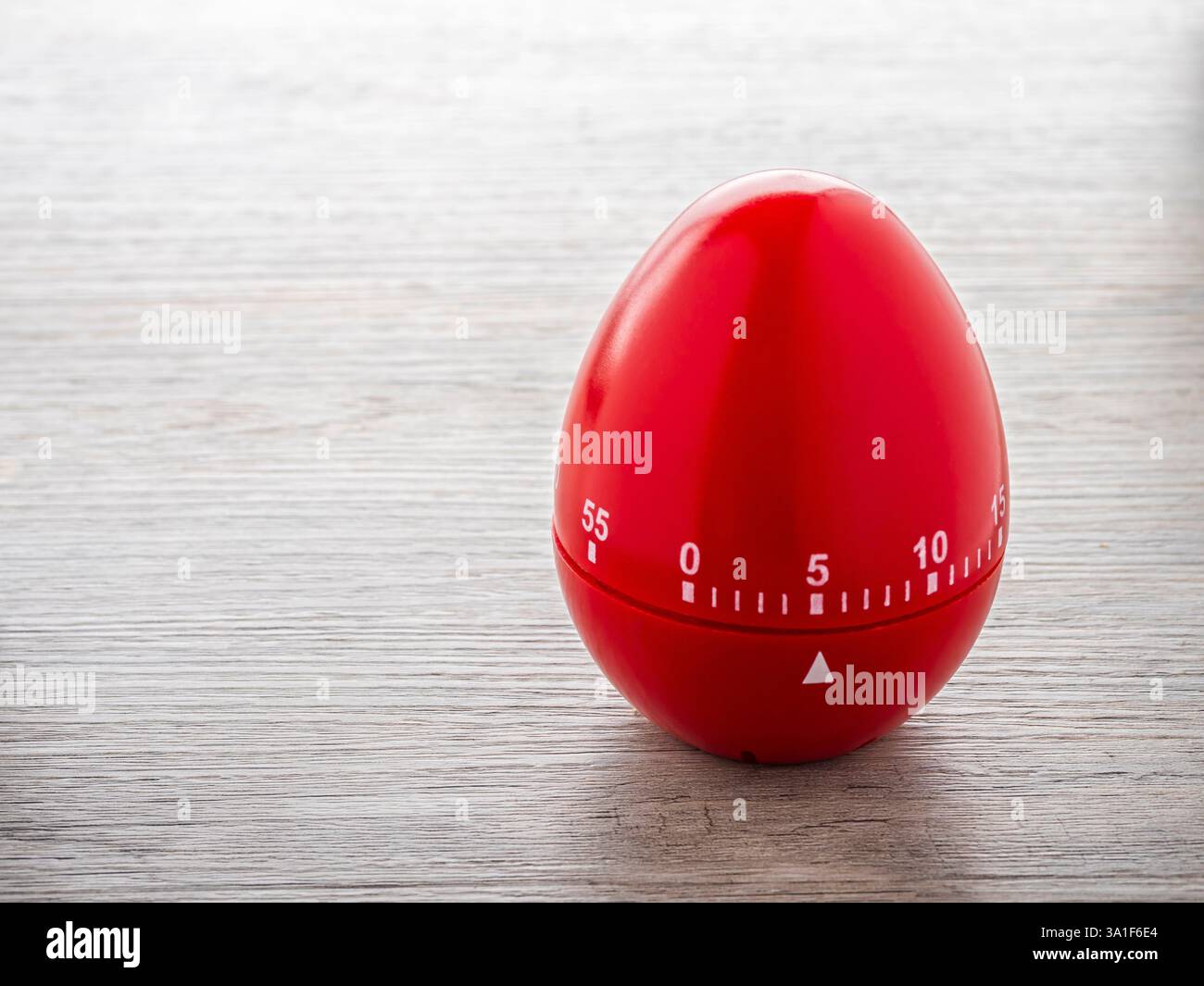 Timer delle uova da cucina rosso su un tavolo da cucina in legno Foto Stock