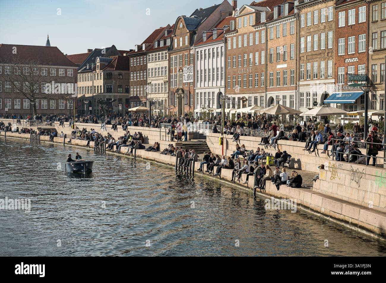 Primavera a Copenaghen e persone che prendono il sole sulla banchina del canale Frederiksholms, 8 marzo 2025 Foto Stock