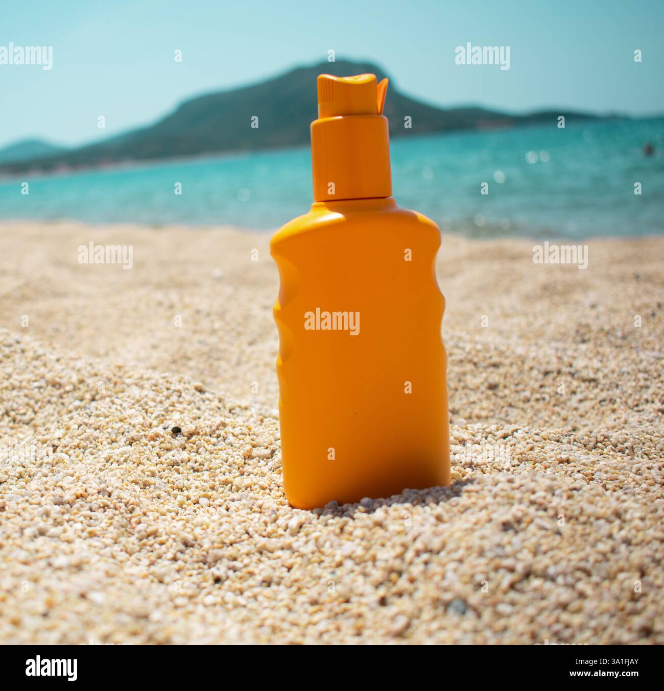 Crema solare arancione in spiaggia. Estate sulla spiaggia con crema solare. Mare e cielo blu sfondo reale. Spazio per il testo. Protezione della pelle Foto Stock