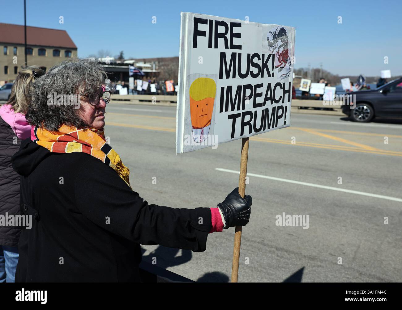Ginevra, Illinois, Stati Uniti. 8 marzo 2025. La protesta JENNIFER CALHOUN di Ginevra, Illinois, ha un segno che recita "Fire Musk, Impeach Trump" durante un raduno nazionale per la festa della donna. (Credit Image: © H. Rick Bamman/ZUMA Press Wire) SOLO PER USO EDITORIALE! Non per USO commerciale! Foto Stock