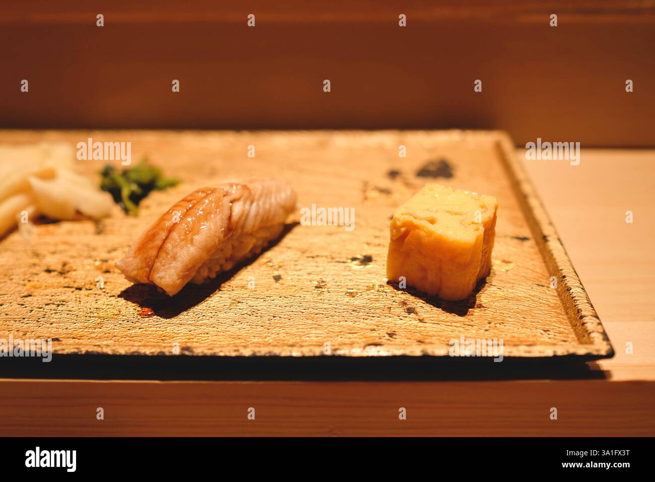 Anago nigiri (sushi di anguille di acqua salata) servito con un piccolo cubo di tamagoyaki (frittata dolce all'uovo giapponese) e zenzero sottaceto in un pranzo omakase a Tokyo Foto Stock