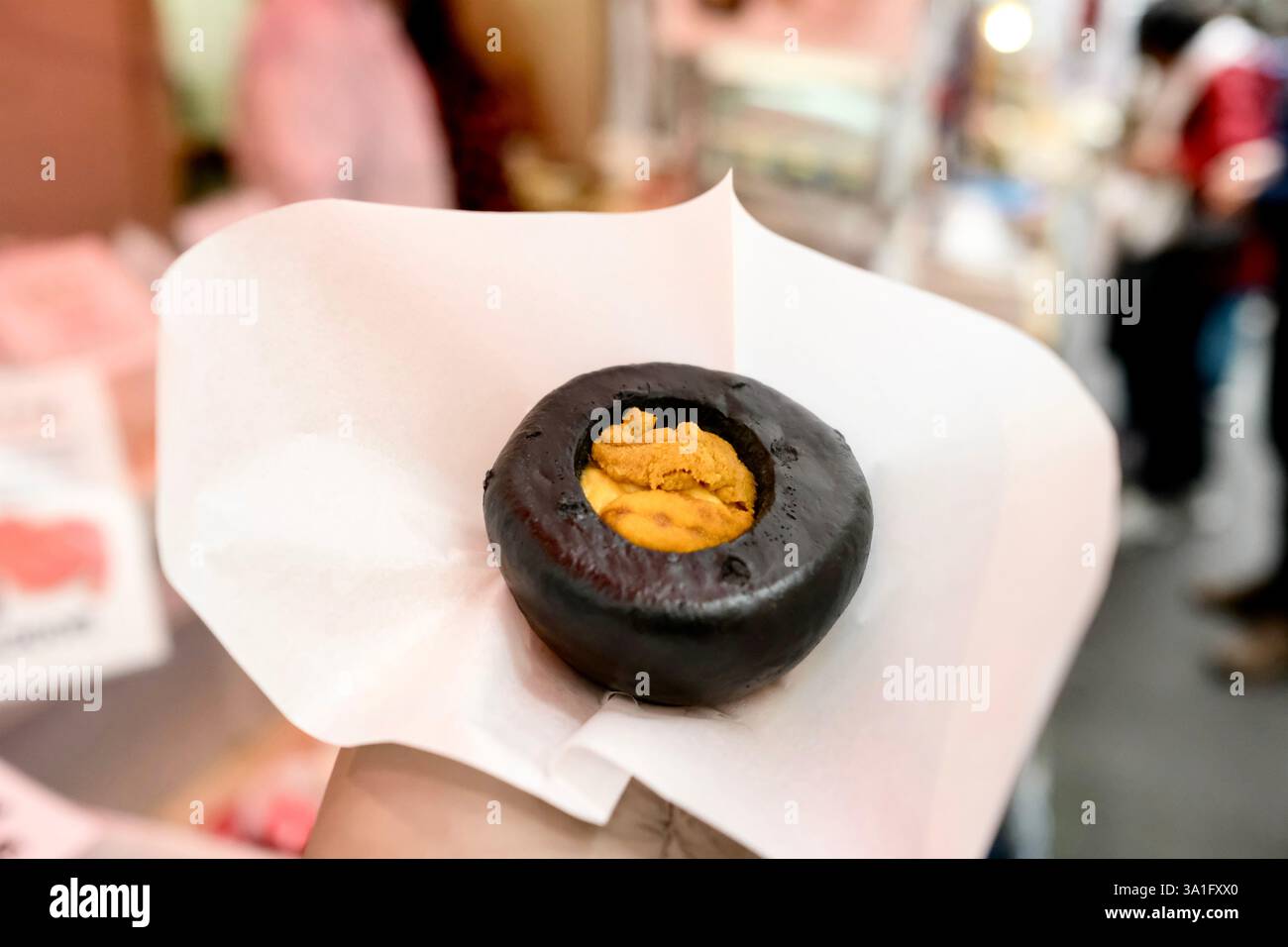 Panino di ricci di mare al vapore di Hamada Shoten, tenuto in mano a una donna al Tsukiji Outer Fish Market di Chuo, Tokyo, Giappone Foto Stock