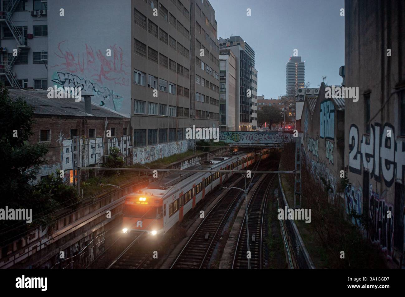 Un treno si sposta lungo i binari che attraversano il quartiere di Poblenou a Barcellona. Le interruzioni e i ritardi nel servizio ferroviario fornito da Renfe ADIF in Catalogna stanno generando sempre più proteste da parte degli utenti. Foto Stock