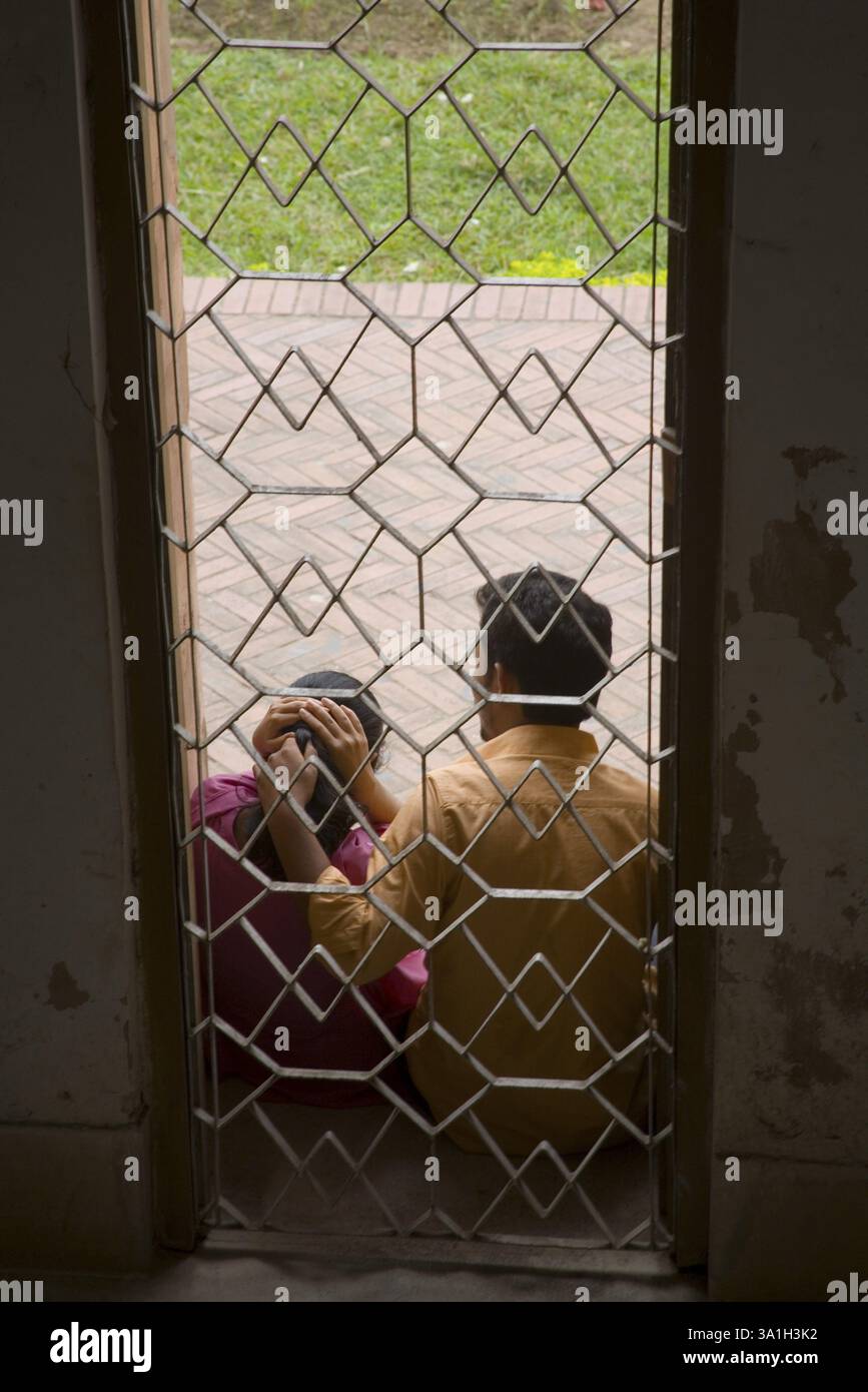 Ragazzo e ragazza seduti vicino alla prigione metallica di Lalbagh Fort, Dacca, Bangladesh, Asia Foto Stock
