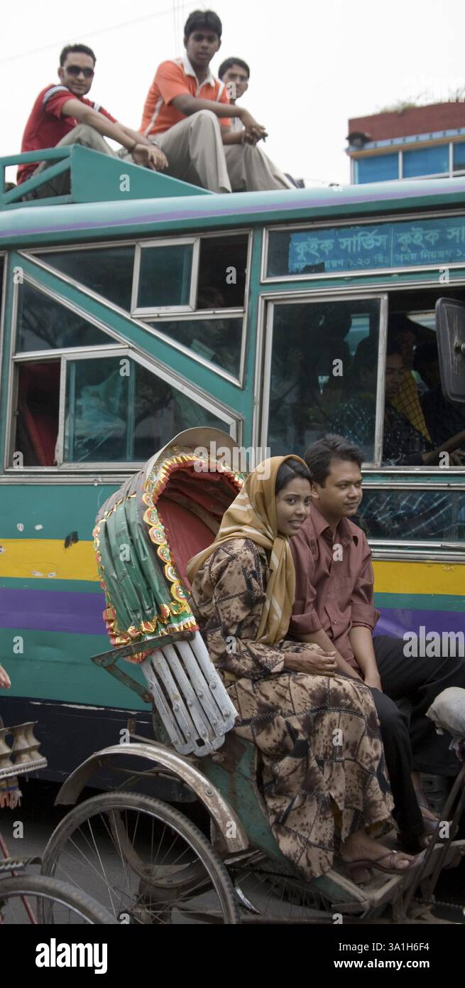 Caos del traffico stradale, persone che viaggiano sul tetto dell'autobus e coppie sedute in risciò, Dacca, Bangladesh, Asia Foto Stock