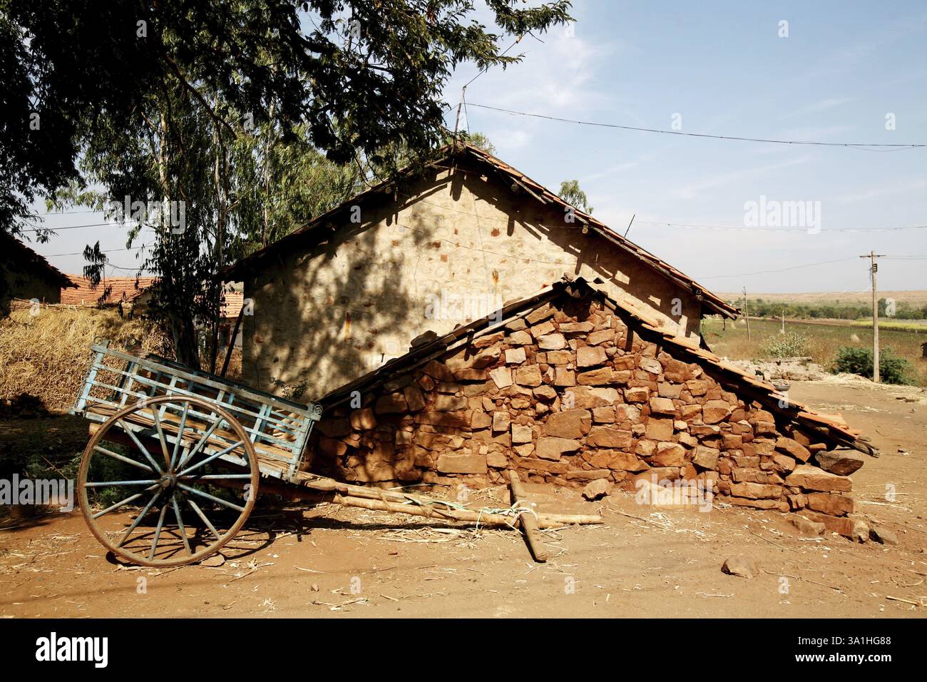 Carrello senza buoi parcheggiato fuori da una casa di pietra, villaggio di Bassapur, Karnataka, India, Asia Foto Stock