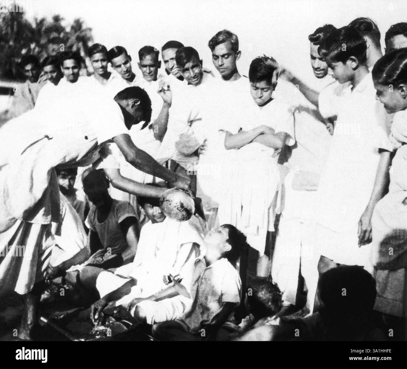 L'acqua viene servita attraverso un imbuto agli harijans che consumano i loro pasti a Chandipur, Noakhali nel Bengala orientale, rivolte ai musulmani indù Foto Stock