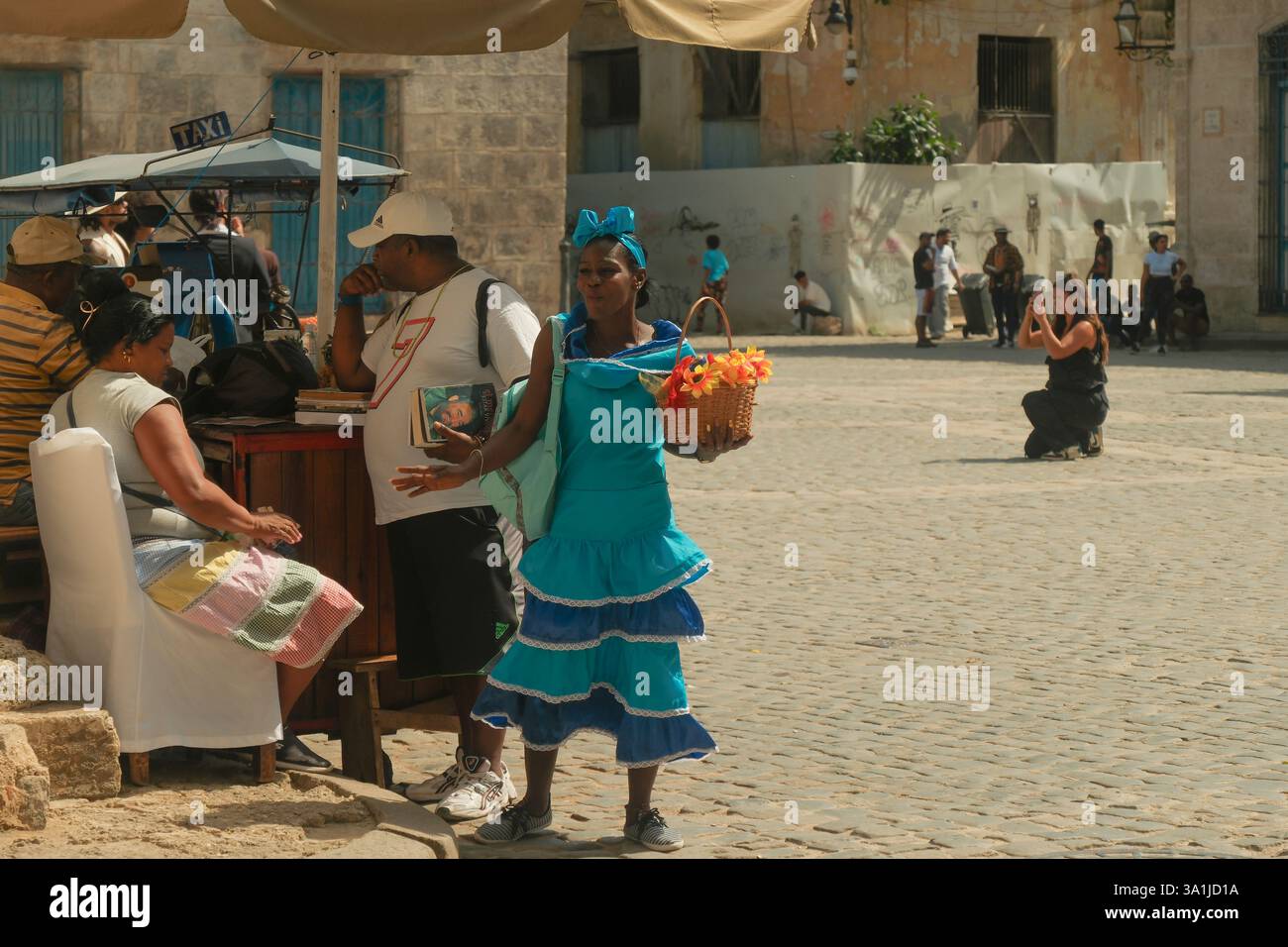 Havana, Cuba 2024 Apr17 - scena di strada di venditori e donna cubana in plaza Square, l'Avana Vecchia. Donna vestita con un colorato abbigliamento tradizionale chiamato R. Foto Stock