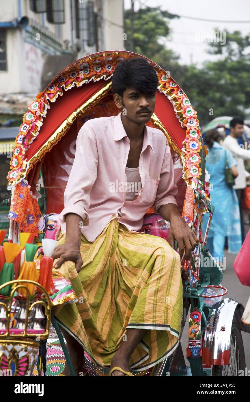 Pedala con l'estrattore di risciò indossando lungi e camicia seduti sul suo veicolo in attesa del passeggero, Dacca, Bangladesh, Asia Foto Stock