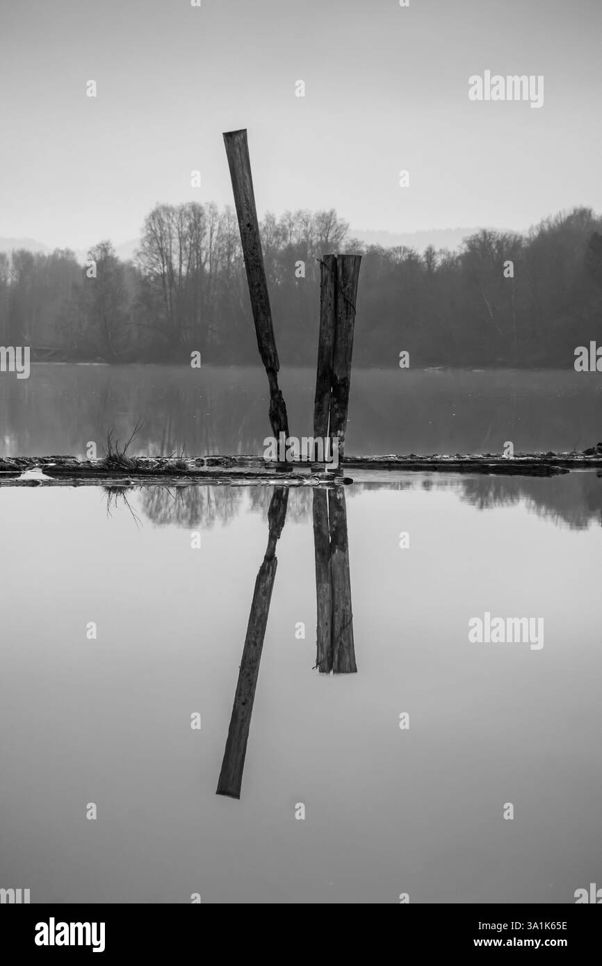Le vecchie passerelle in legno e le boatouses rosse si riflettono nell'acqua poco profonda, raccontando storie di tempo che passa Foto Stock