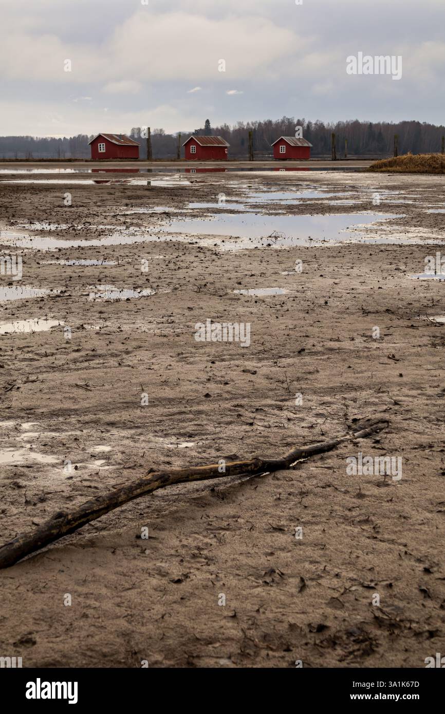 Le vecchie passerelle in legno e le boatouses rosse si riflettono nell'acqua poco profonda, raccontando storie di tempo che passa Foto Stock