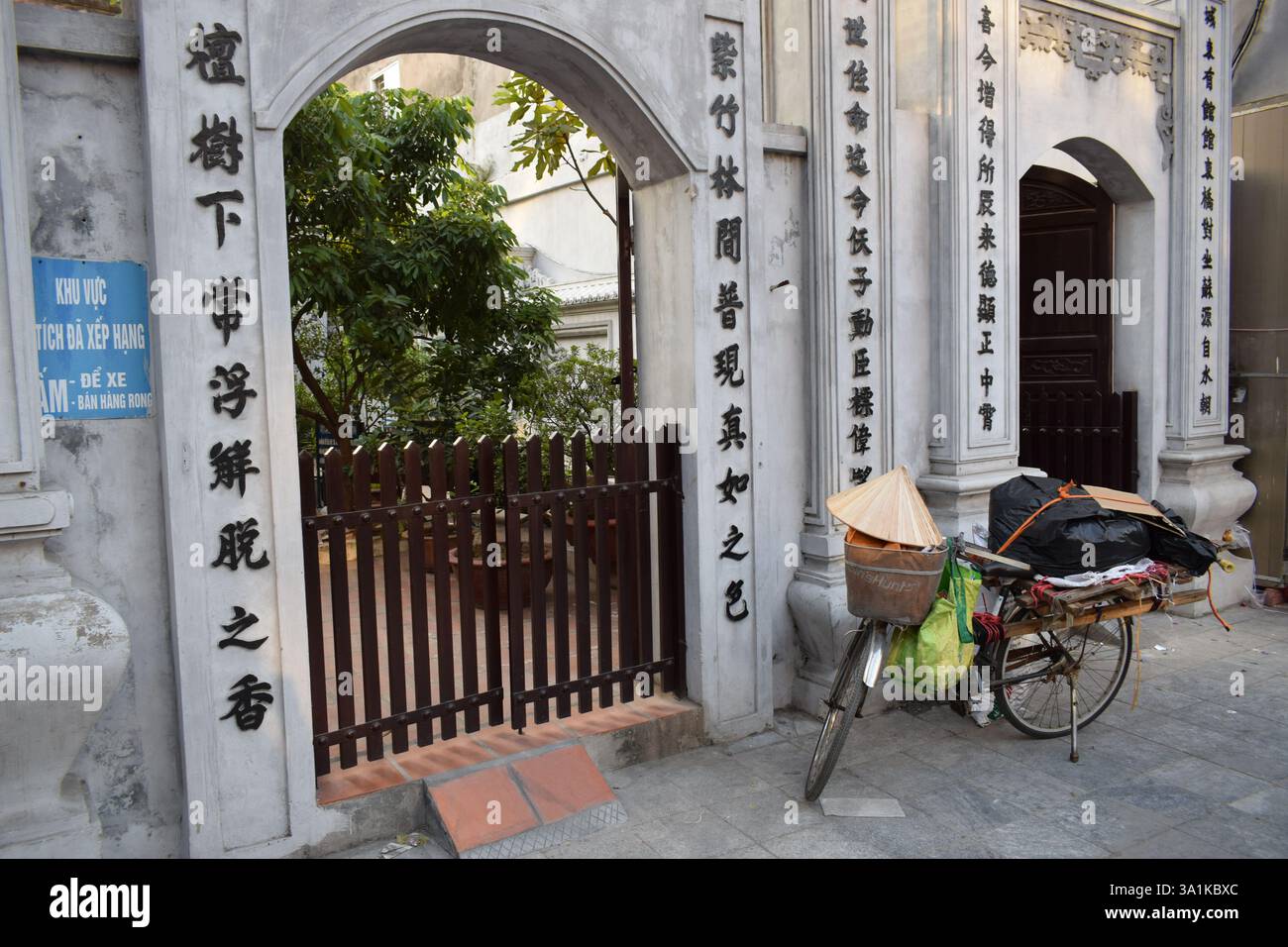 Una bicicletta con un tradizionale cappello vietnamita si trova di fronte a una tipica casa vietnamita. L'affascinante scena riflette la semplicità e la cultura Foto Stock