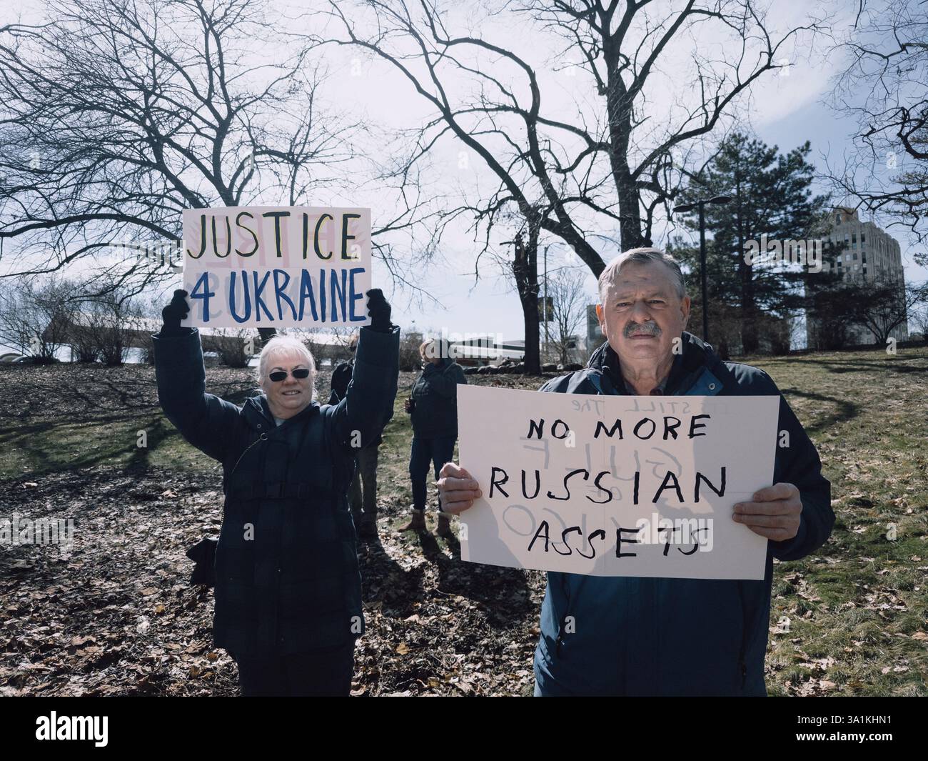 Un uomo e una donna con segni a sostegno dell'Ucraina, con Justice 4 Ukraine e No More Russian Assets, al raduno della giornata internazionale della donna a Flint - Immagine stock catturata con smartphone
