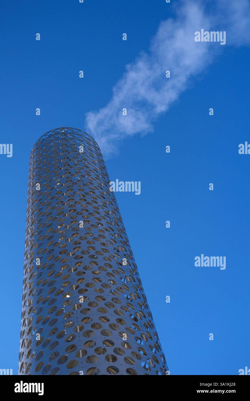 Caldaie industriali o tubi di scarico per stazioni termiche, ricoperti da una facciata decorativa perforata con intagli circolari, rilasciano fumo o vapore in Foto Stock