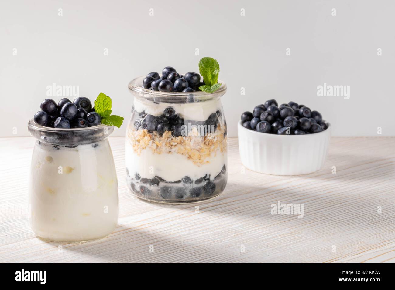 Yogurt con muesli, mirtillo e menta in vasetti di vetro mirtillo fresco in ciotola sana colazione biologica con probiotici Berry parfait Sust Foto Stock