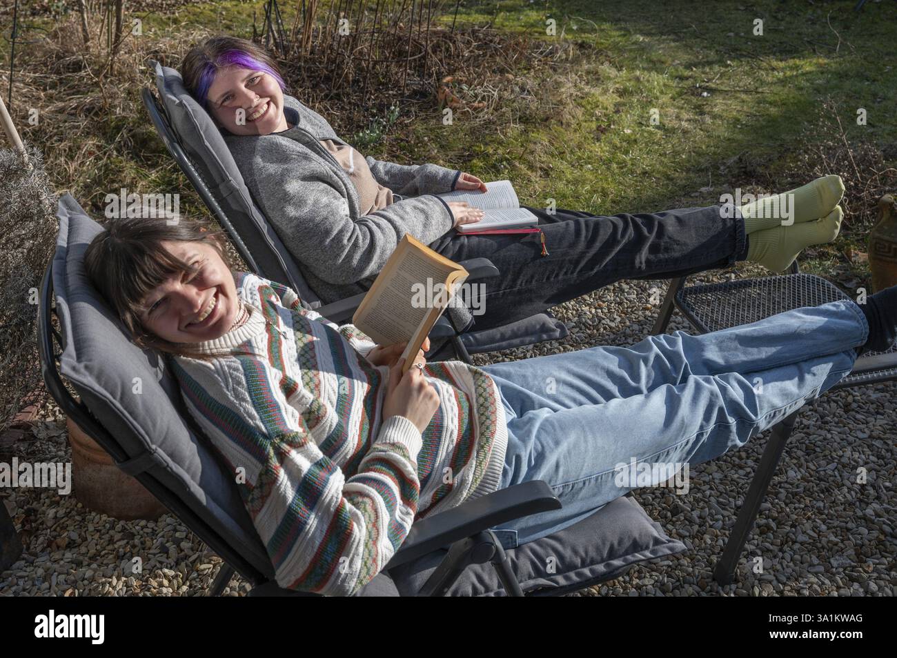 Due giovani donne in una sdraio che leggono in giardino, Baviera, Germania, Europa Foto Stock