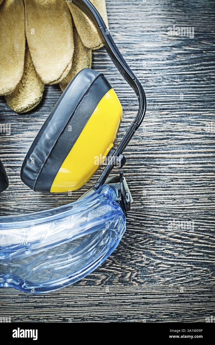 Occhiali protettivi guanti cuffie su tavola di legno Foto Stock