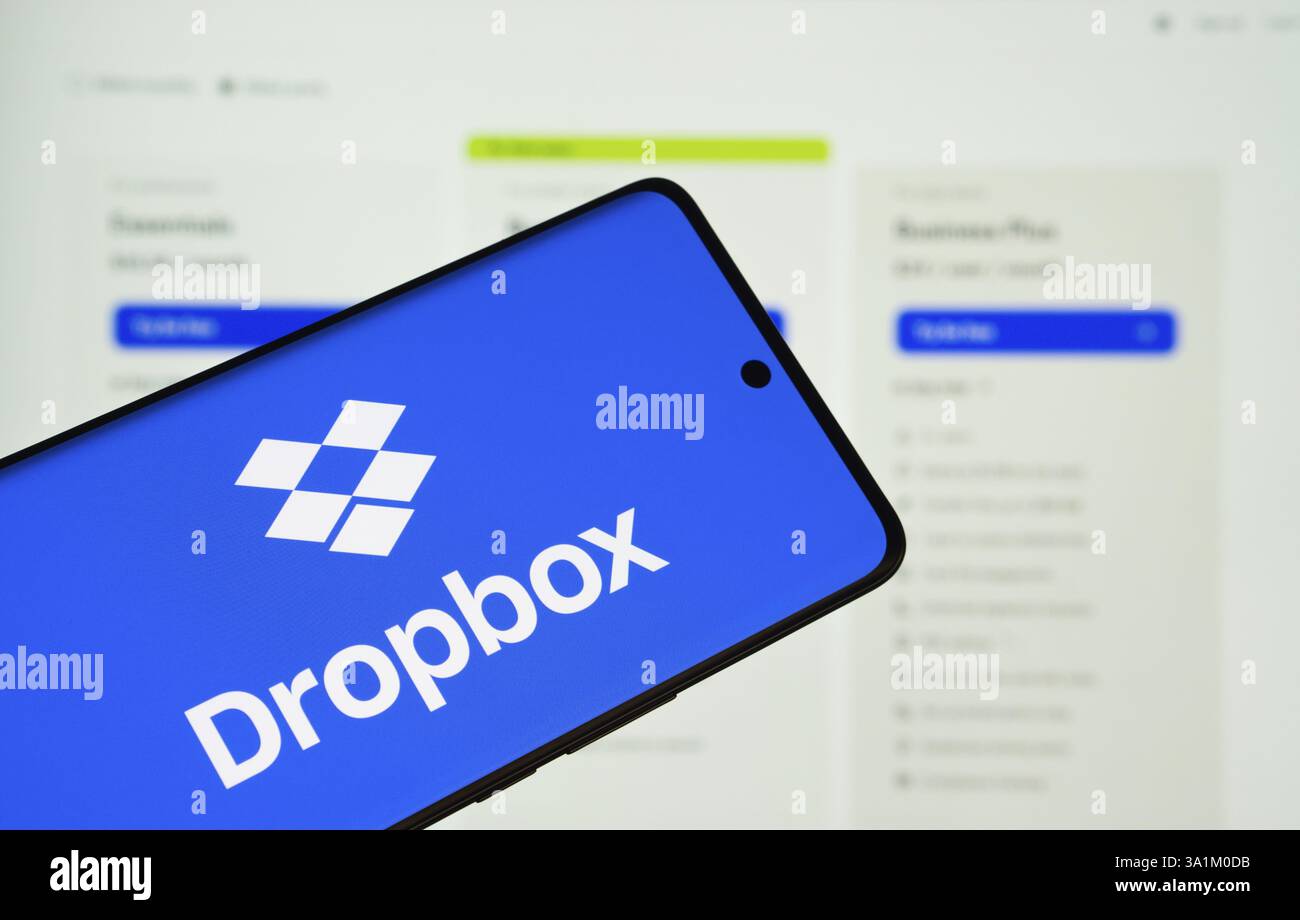 Il logo Dropbox viene visualizzato sullo schermo di uno smartphone, con il sito Web Dropbox visibile sullo schermo di un computer sullo sfondo Foto Stock