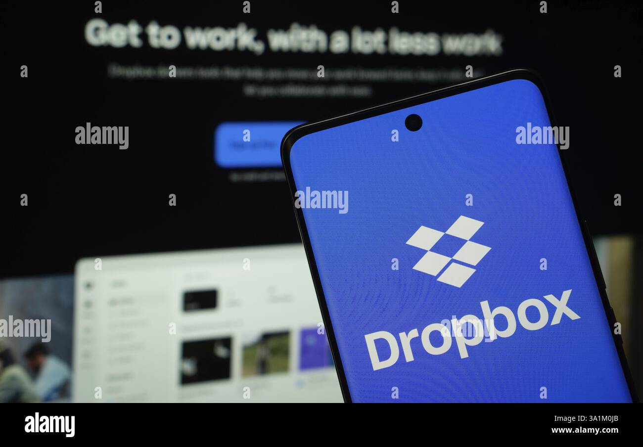 Il logo Dropbox viene visualizzato sullo schermo di uno smartphone, con il sito Web Dropbox visibile sullo schermo di un computer sullo sfondo Foto Stock