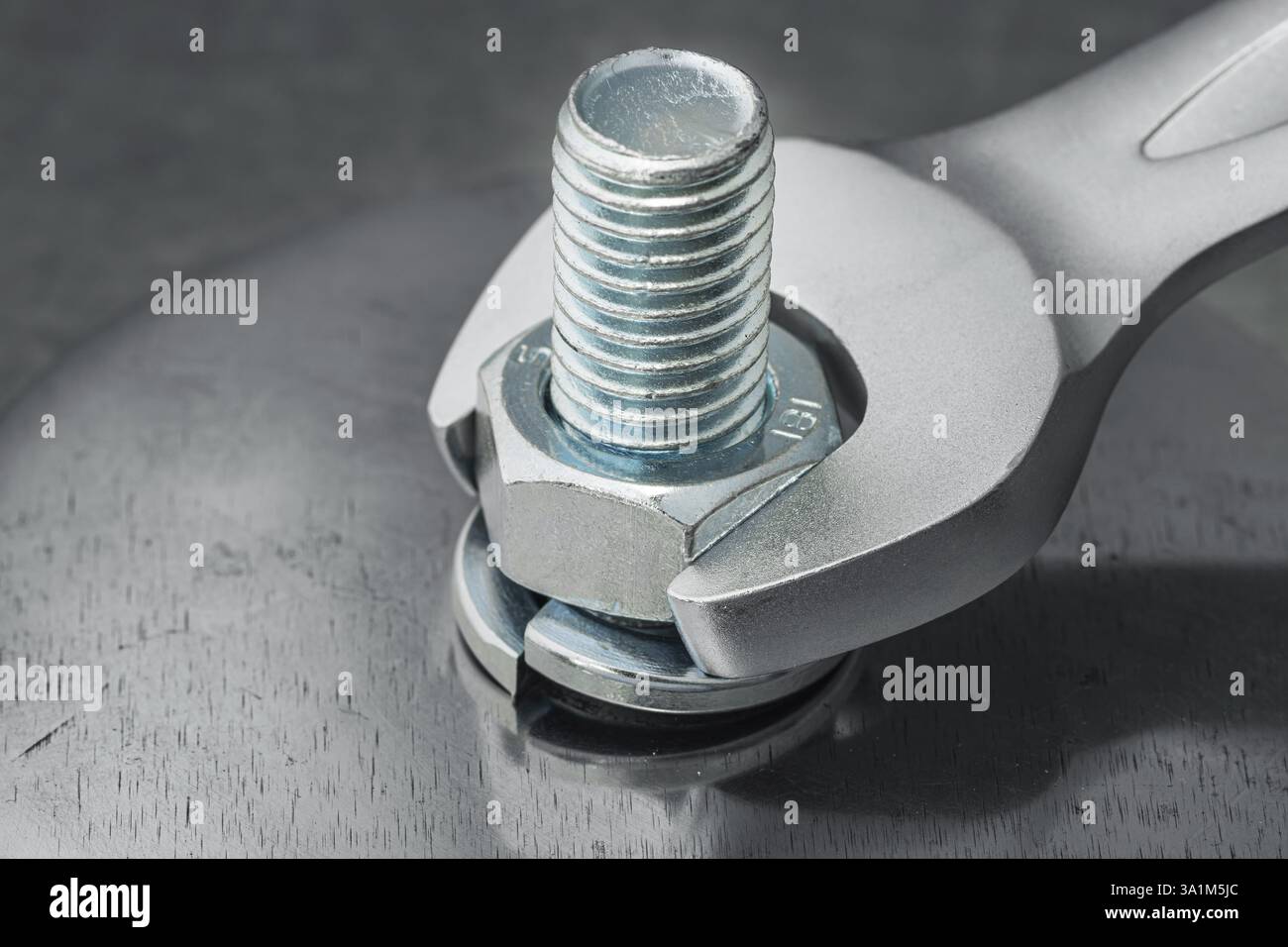 La chiave a estremità aperta consente di serrare il dado sul bullone con incisore rondella in dettaglio acciaio sulla piastra in acciaio metallico Foto Stock