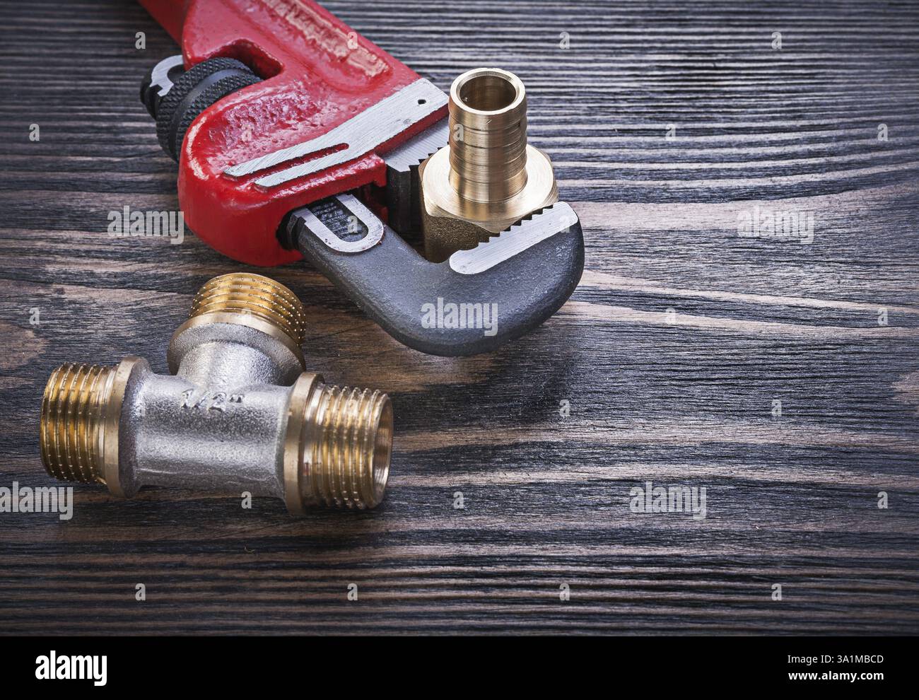 Raccordo a T uguale in ottone per tubi metallici su pannello di legno Foto Stock