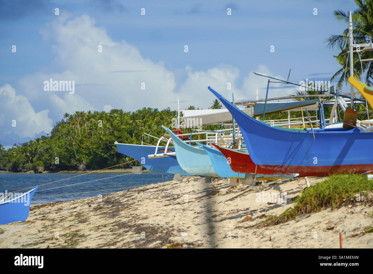 Le tradizionali barche da pesca, kNAwn AS bangka, che riposano sulla spiaggia sabbiosa dell'isola di guyam a siargao, filippine, creano un vibrante contrasto wi Foto Stock