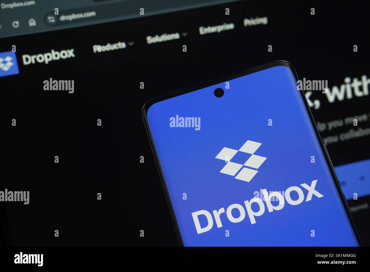 Il logo Dropbox viene visualizzato sullo schermo di uno smartphone, con il sito Web Dropbox visibile sullo schermo di un computer sullo sfondo Foto Stock