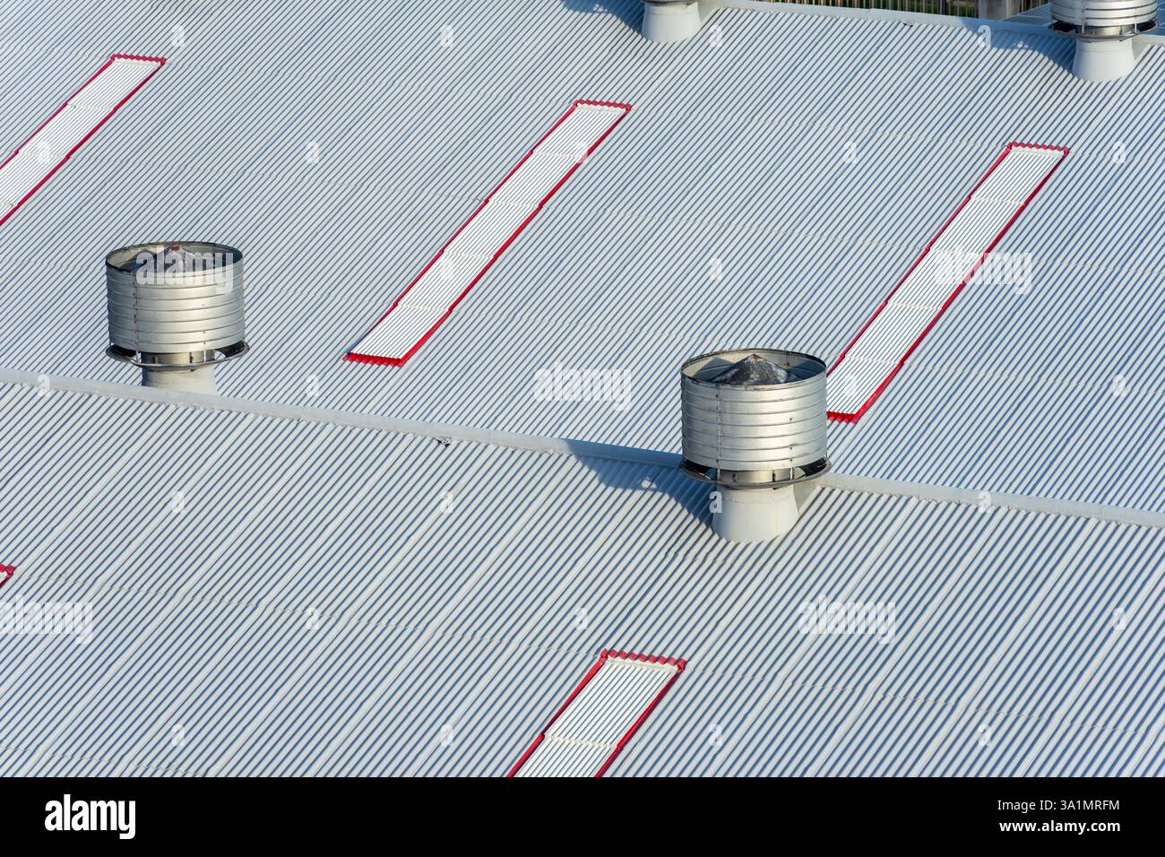Tetto in metallo stagno con ventilatori a gravità per il flusso di sfiato dell'aria verso gli edifici commerciali Foto Stock