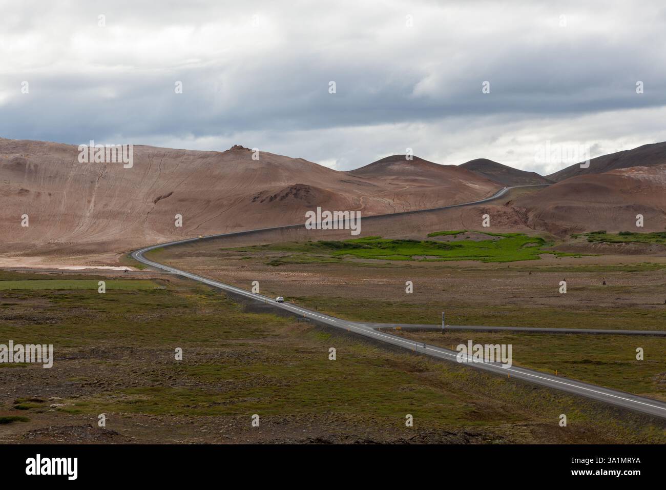 Strada dell'Islanda con montagne marroni all'orizzonte. Strada vuota nel paesaggio rurale islandese. Crocevia vicino all'area geotermica di Hverir e Krafla. Foto Stock