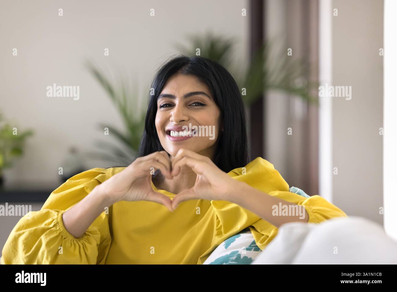 Donna indiana felice che mostra il simbolo del cuore con le dita unite Foto Stock