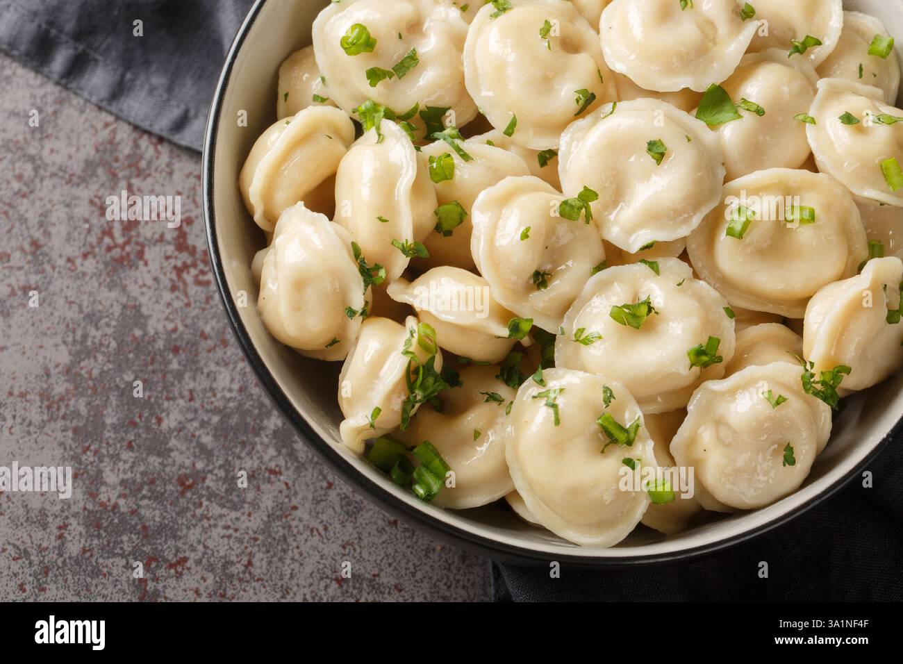 Polpette di carne fatte in casa o Pelmeni con prezzemolo fresco sul piatto primo piano sul tavolo. Vista dall'alto orizzontale Foto Stock