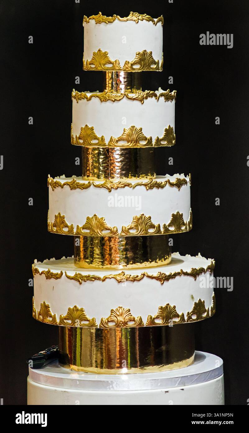 Torta ornamentale per matrimoni tradizionale, alta e gustosa, con glassa bianca e decorazioni dorate Foto Stock