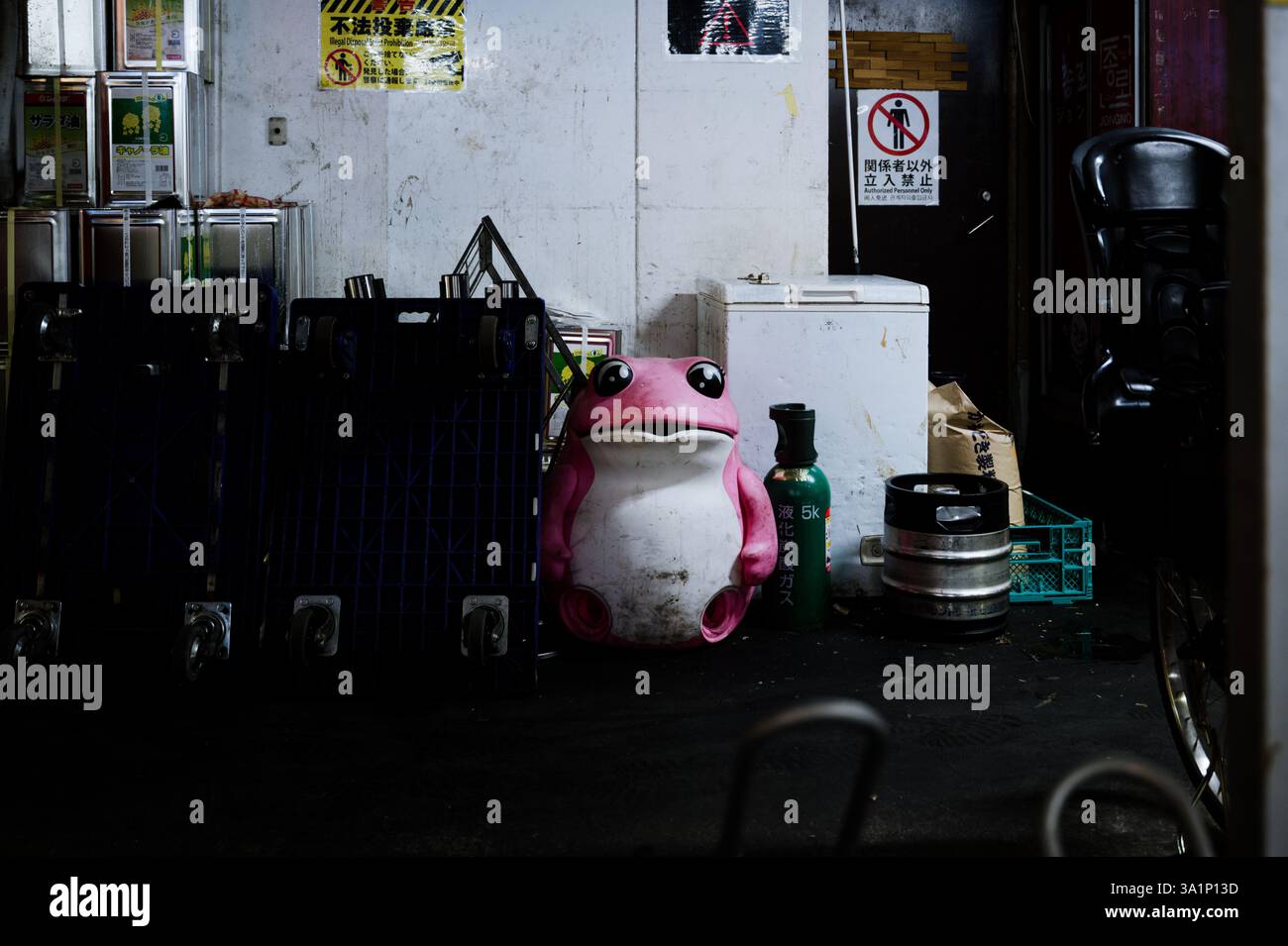 Una rana rosa abbandonata si trova tra gli oggetti industriali sparsi, in un vicolo posteriore di Shinjuku Foto Stock