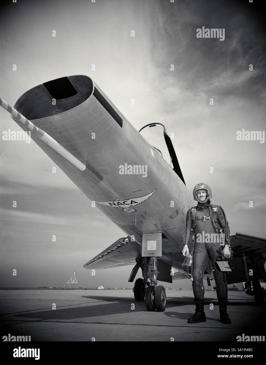 George Cooper, pilota collaudatore del National Advisory Committee for Aeronautics, o NACA, si trova accanto ad un F-100 nordamericano, un caccia supersonico testato dalla NACA. Foto Stock