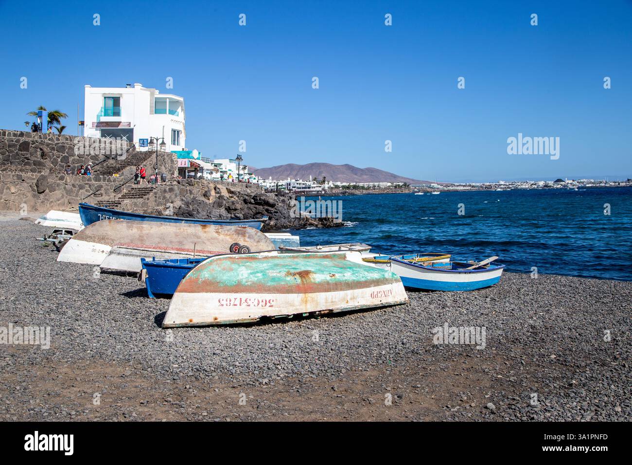 Piccole barche da pesca sulla spiaggia di ciottoli presso la località turistica spagnola di Playa Blanca sull'isola delle Canarie di Lanzarote Foto Stock
