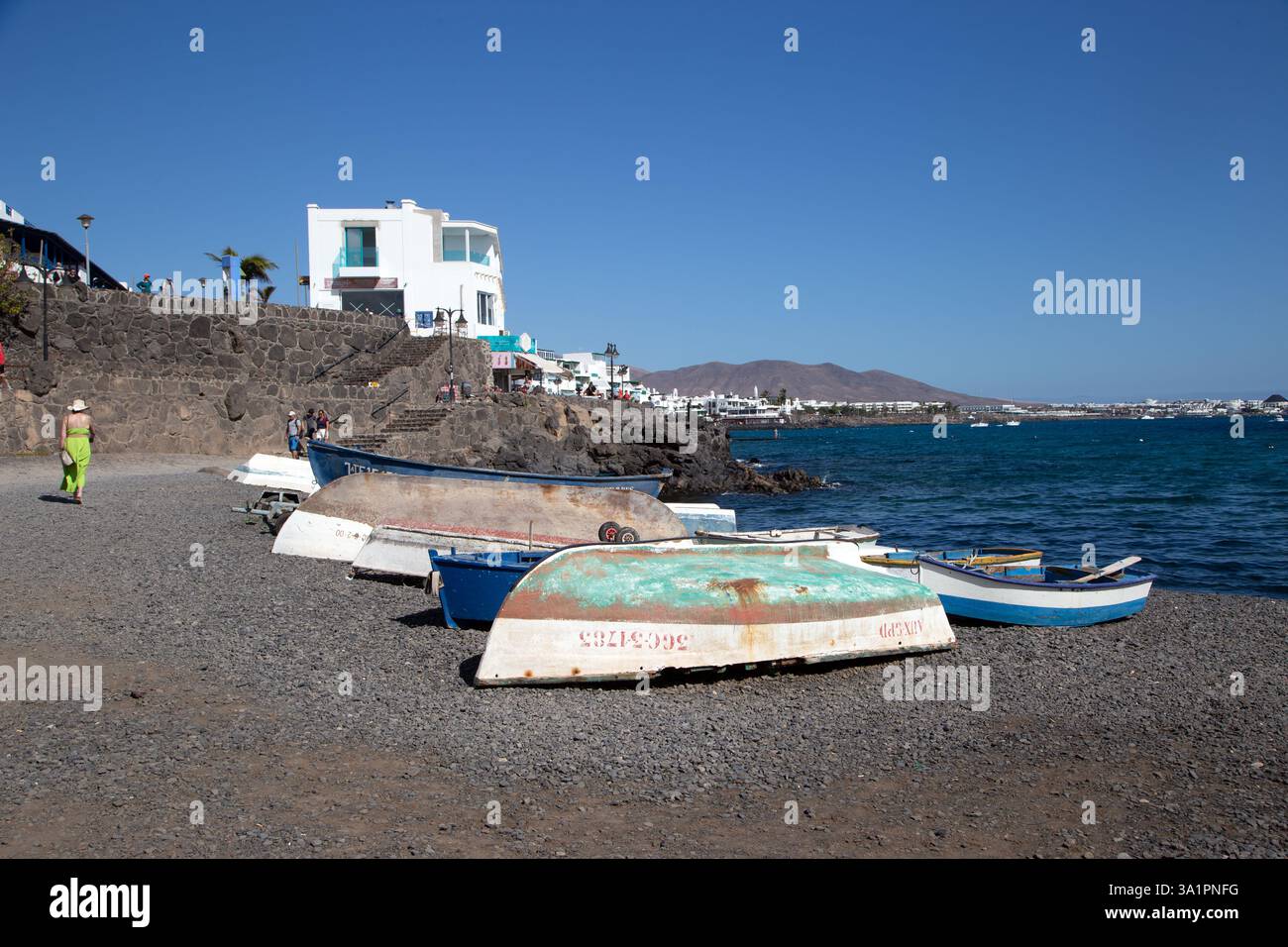 Piccole barche da pesca sulla spiaggia di ciottoli presso la località turistica spagnola di Playa Blanca sull'isola delle Canarie di Lanzarote Foto Stock