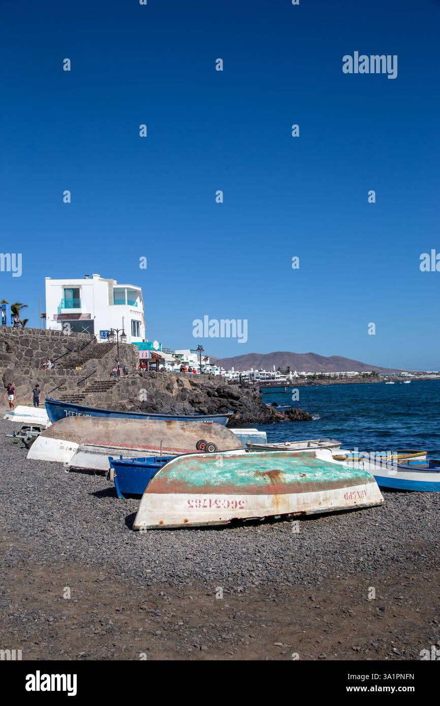 Piccole barche da pesca sulla spiaggia di ciottoli presso la località turistica spagnola di Playa Blanca sull'isola delle Canarie di Lanzarote Foto Stock