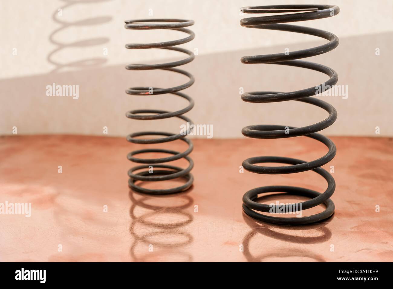 Molle metalliche sulla superficie in rame. Luce solare. Riflessione e ombra. Molle utilizzate nell'ingegneria meccanica e nella costruzione di aeromobili. Copia spazio. Foto Stock