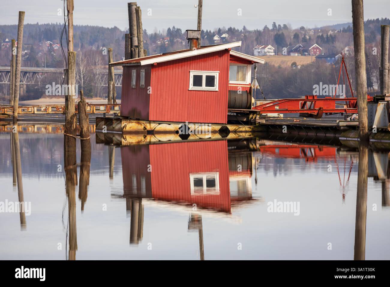 Le vecchie passerelle in legno e le boatouses rosse si riflettono nell'acqua poco profonda, raccontando storie di tempo che passa Foto Stock